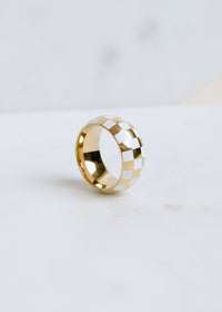 gold and white checkered band ring displayed on neutral background for a modern look