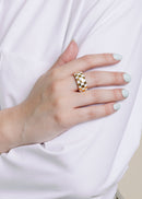 model wearing chunky gold ring with white enamel checkerboard design