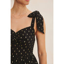 Black dress with gold patterns and a bow detail on a neutral background