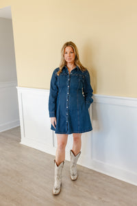 Woman wearing a denim dress and white cowboy boots standing against a wall with a color block design.