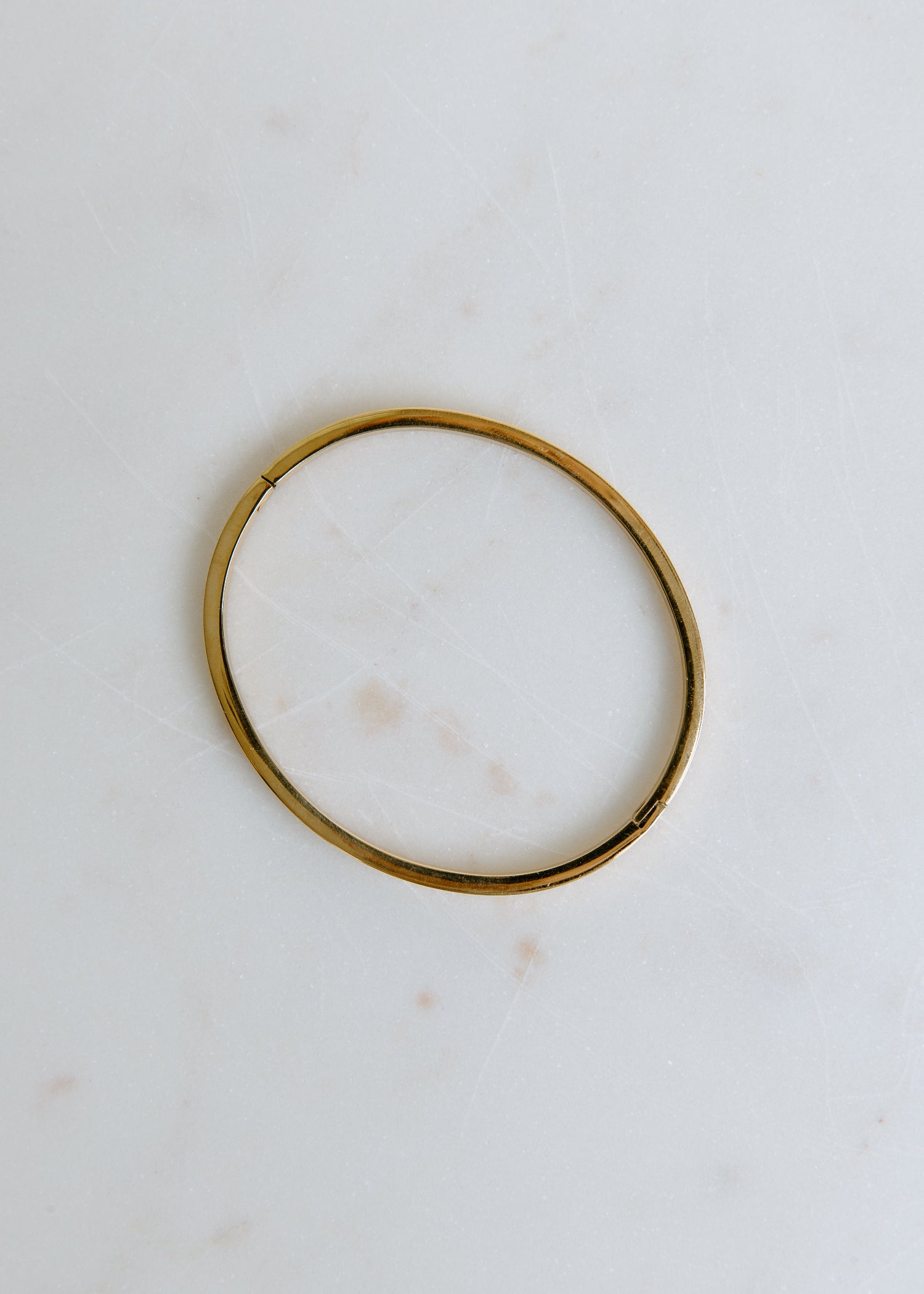 elegant open gold bangle displayed on white surface for a modern look