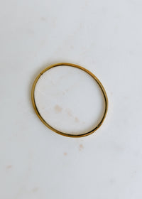 elegant open gold bangle displayed on white surface for a modern look